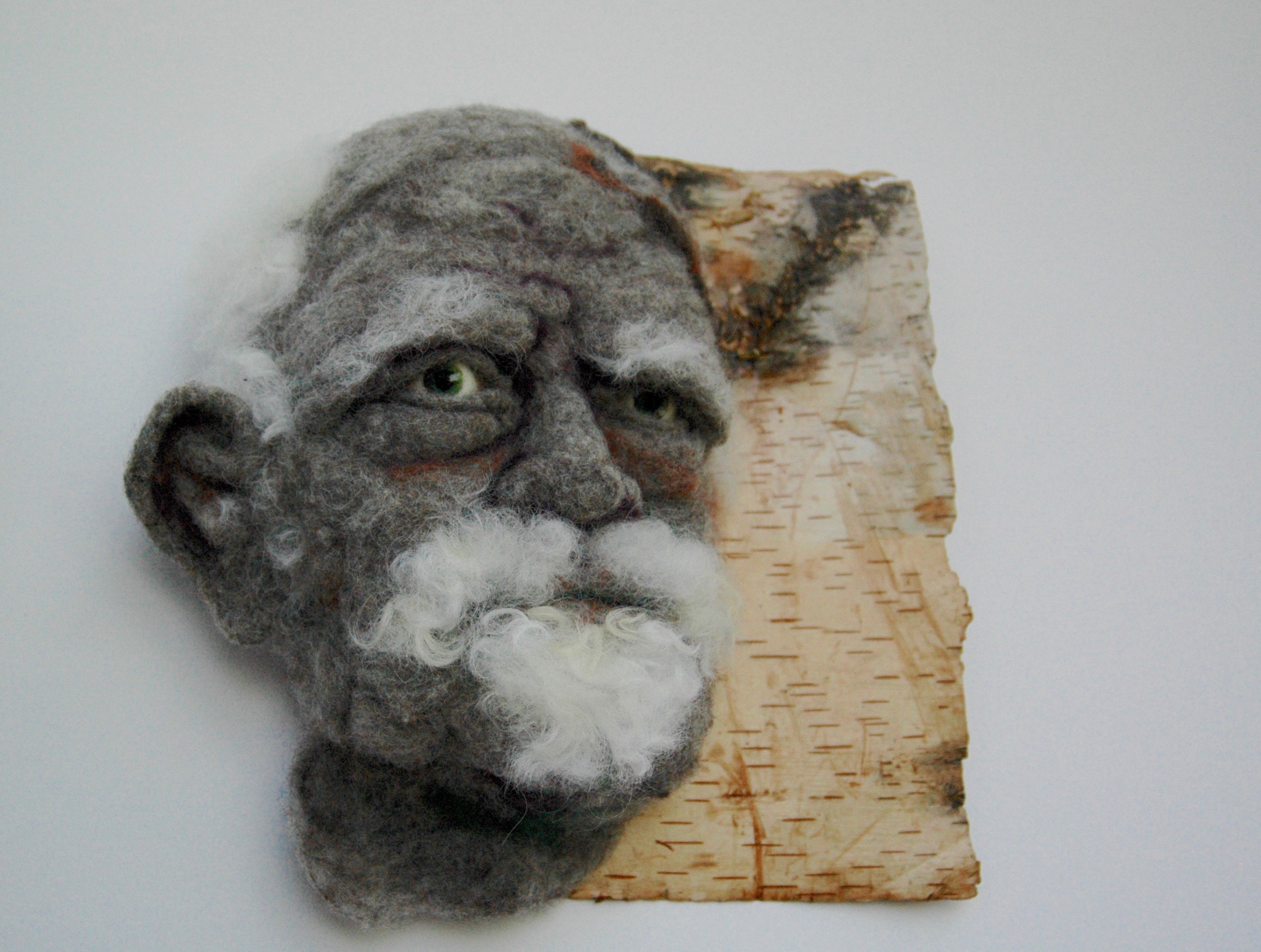 Sortons des bois - Hand needle-felted wool sculpture of a male face – balding with wispy white hair and goatie. Mounted on reclaimed birch bark. Artist/photo: Rosemarie Péloquin