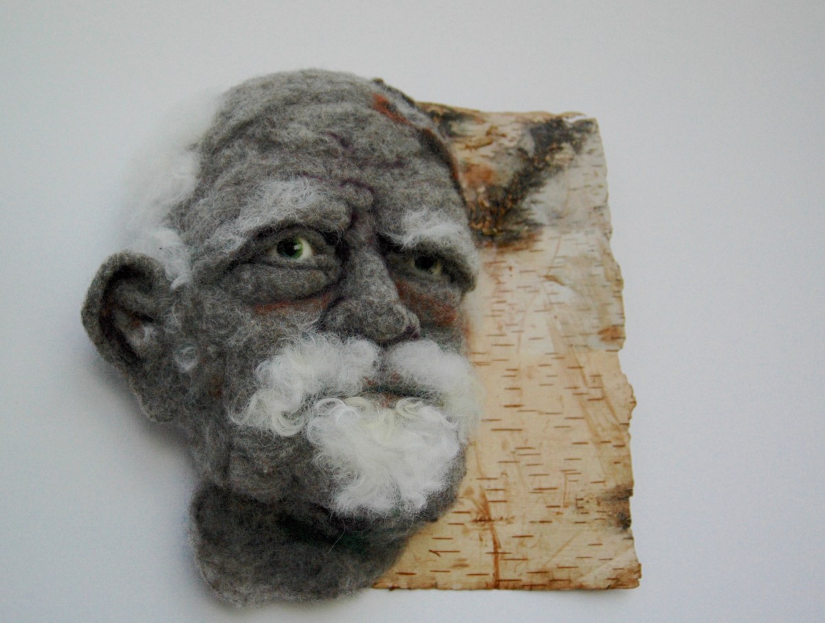 Sortons des bois - Hand needle-felted wool sculpture of a male face – balding with wispy white hair and goatie. Mounted on reclaimed birch bark. Artist/photo: Rosemarie Péloquin