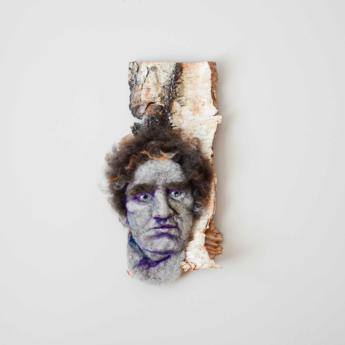 Frédéric - Hand needle-felted wool sculpture of a brown-haired young male face – Mounted on reclaimed birch bark. artist: Rosemarie Péloquin; photo: Emily Christie.