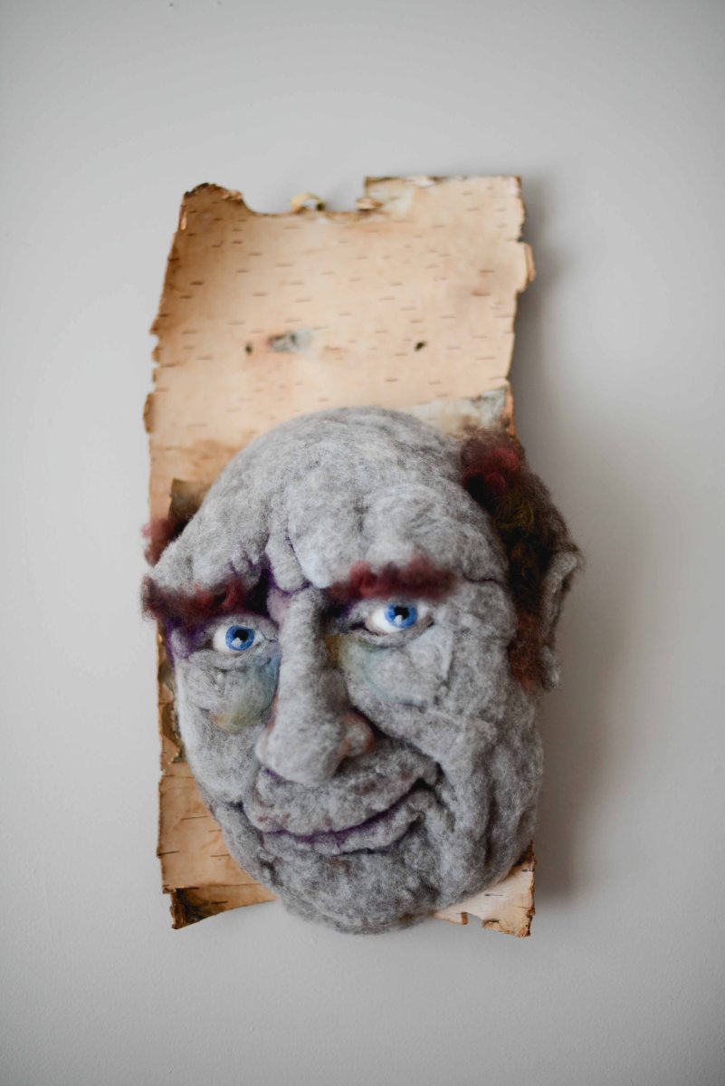 Hugo - Hand needle-felted wool sculpture of a male face – baldish with a slight grin. Mounted on reclaimed birch bark. artist: Rosemarie Péloquin; photo: Emily Christie.
