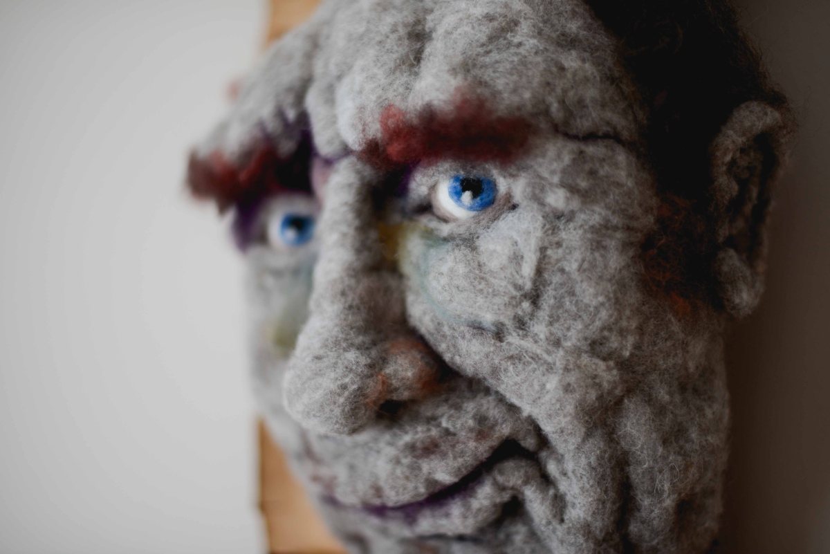 Hugo - Hand needle-felted wool sculpture of a male face – baldish with a slight grin. Mounted on reclaimed birch bark. artist: Rosemarie Péloquin; photo: Emily Christie.